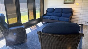 A room with a blue sofa, wicker chairs, and a large window with blinds. - Venice Villas San Marco - Golden Beach (Venice)