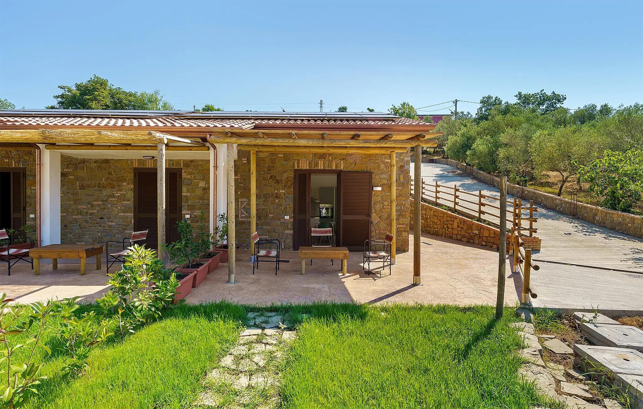 A stone building with a covered patio, outdoor seating, and a stone wall.