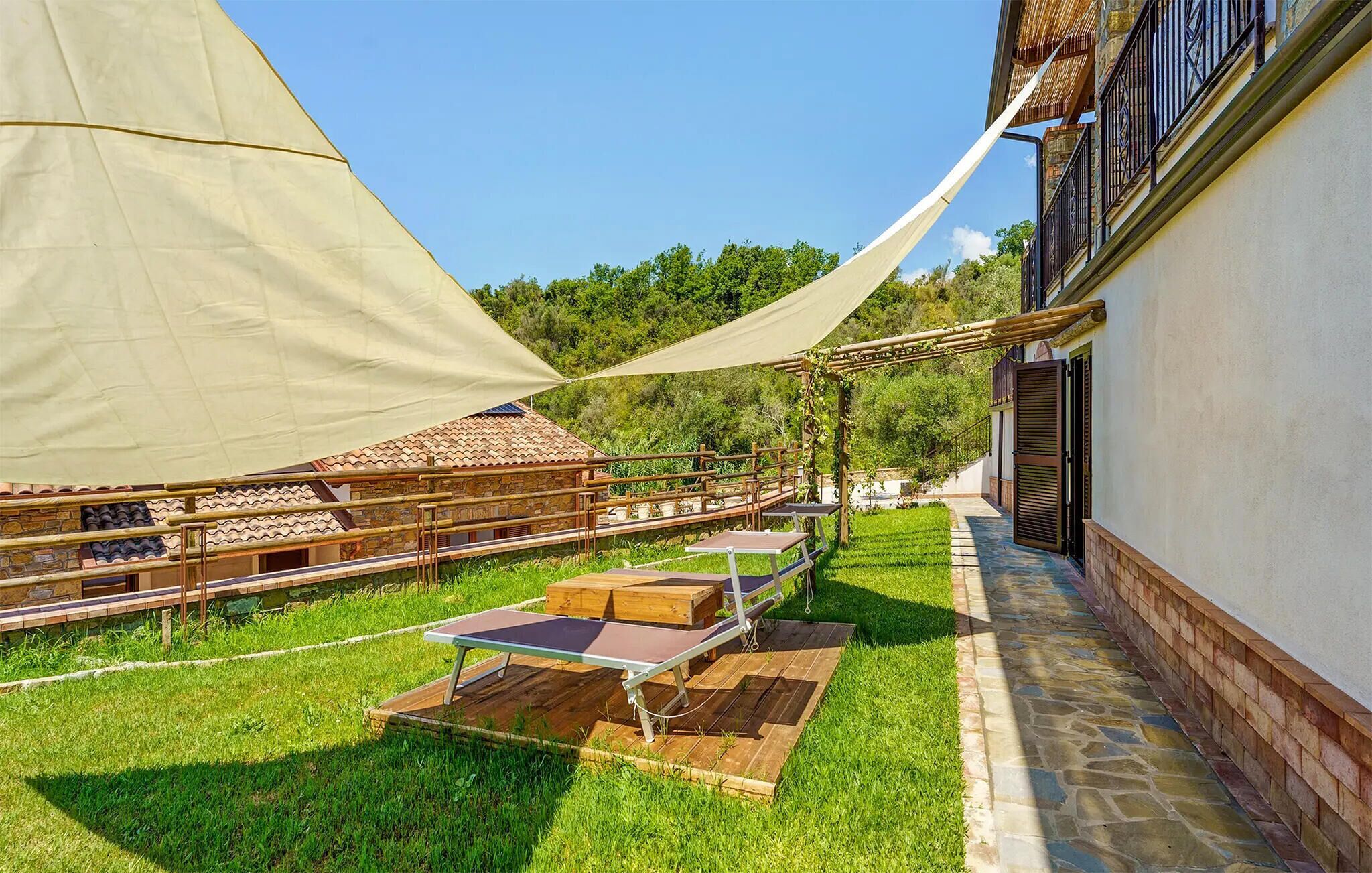 Un espacio exterior con mesas y sillas, una pérgola y un edificio con techo de tejas.
