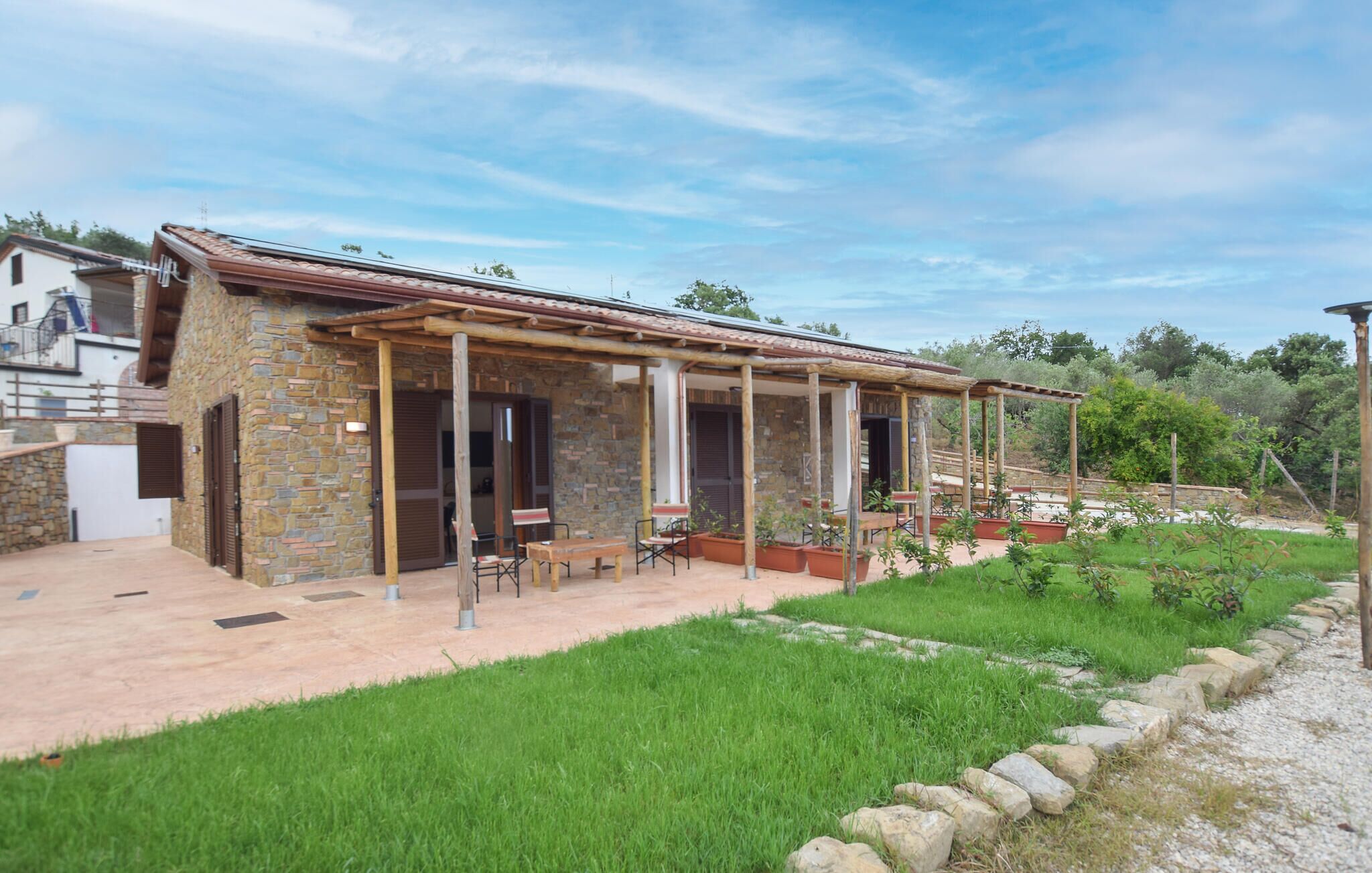 Una casa in pietra con veranda coperta, posti a sedere all'aperto e un giardino.