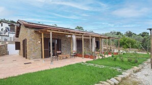 Uma casa de pedra com alpendre, mobiliário de exterior e um jardim.
