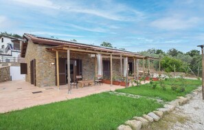 Una casa in pietra con veranda coperta, posti a sedere all'aperto e un giardino.