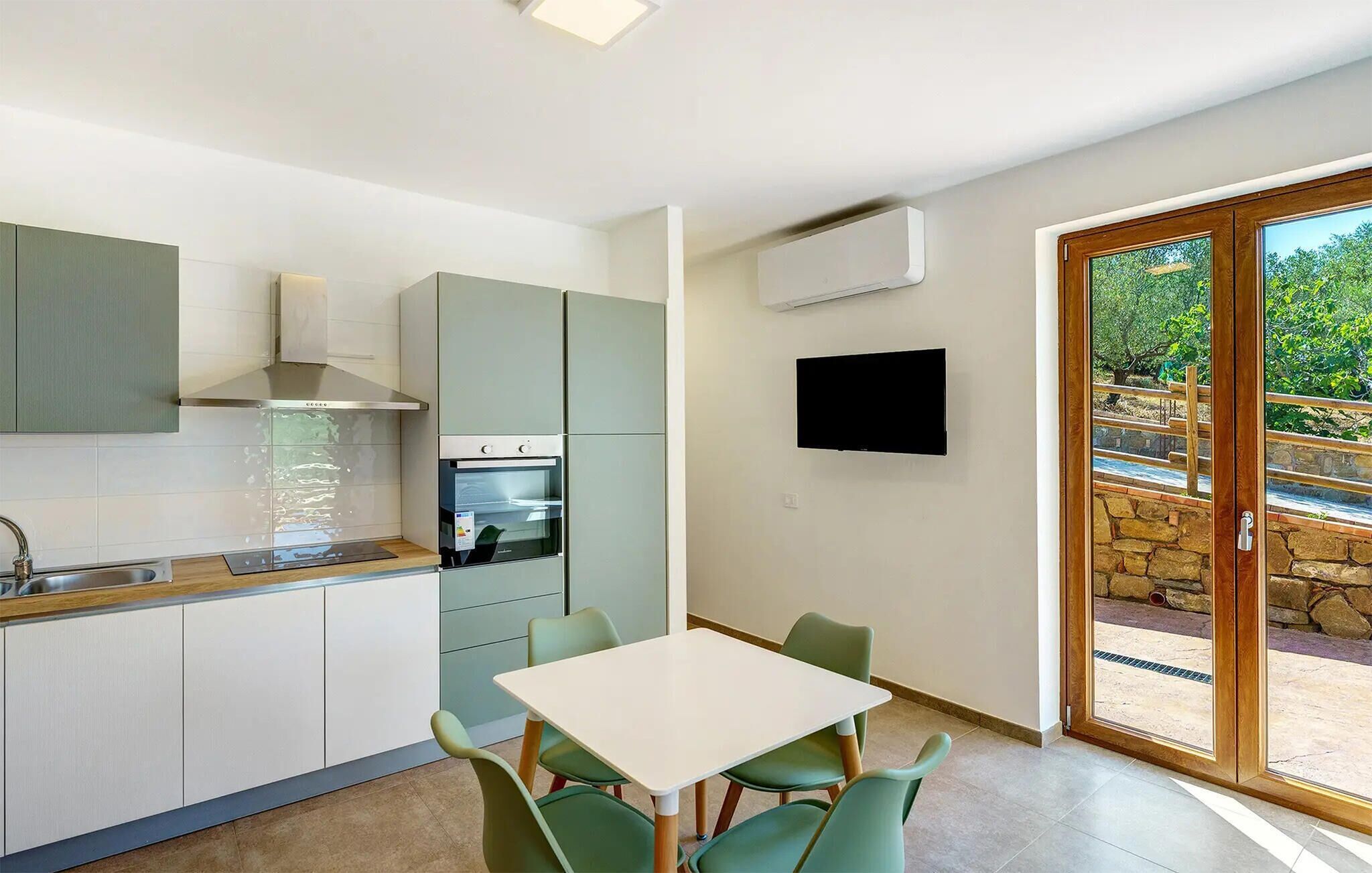 Une cuisine moderne avec un coin repas, un téléviseur à écran plat et une vue sur l’extérieur.
