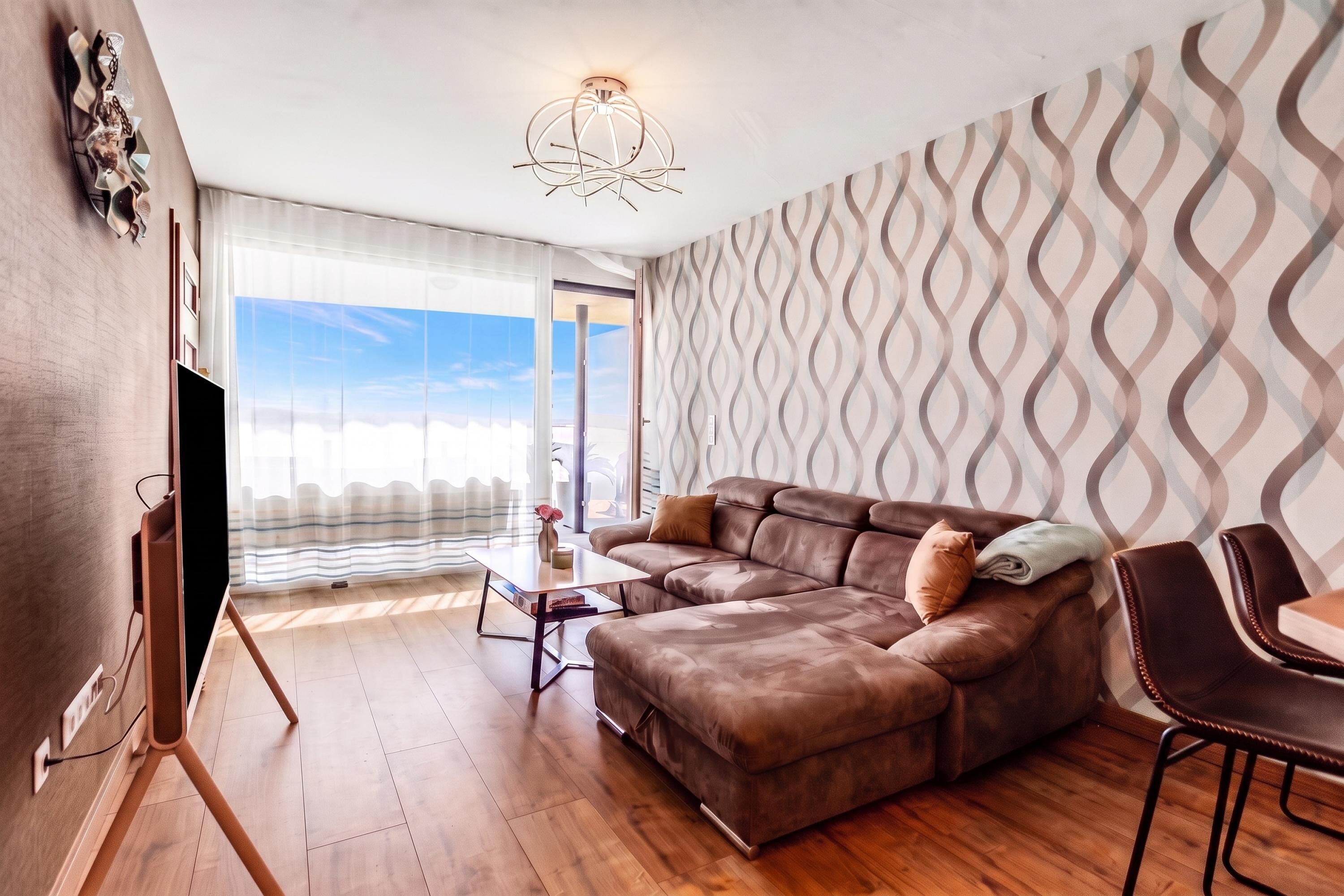 Ein modernes Wohnzimmer mit einem braunen Ledersofa, einem Couchtisch und einem Essbereich mit einem Stuhl.