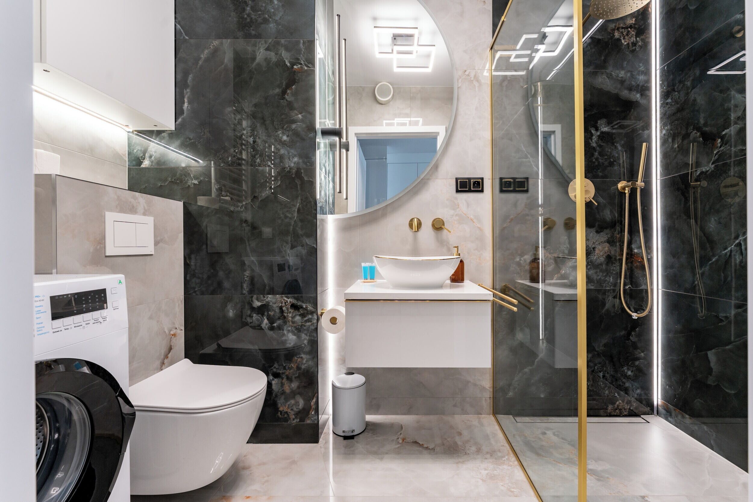 Une salle de bain moderne équipée de toilettes, d’un lave-linge, d’un lavabo et d’une douche.