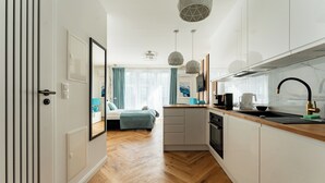 A modern kitchen with white cabinets, a wooden countertop, and a large window. - Mostek Riverside Deluxe Studio (Gdańsk)