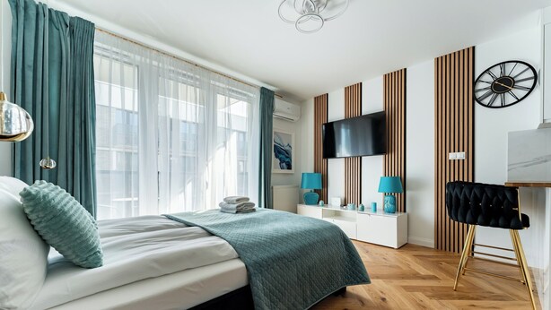A modern hotel room with a bed, a TV, a desk, and a chair. - Mostek Riverside Deluxe Studio (Gdańsk)