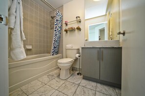 A bathroom with a bathtub, toilet, and a shower curtain. - Delsuites Toronto (Toronto)