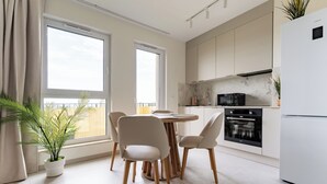 A modern kitchen with a dining area, large windows, and a potted plant. - Rumia Stylish Apartment (Rumia)