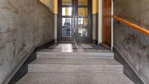 A staircase with a wooden handrail, a double door with glass panels, and a wall-mounted bulletin board. - Spokojna Comfort Studio (Kraków)