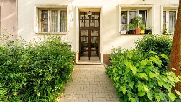 A building with a central entrance, a number '13' above the door, and a small balcony with potted plants. - Spokojna Comfort Studio (Kraków)