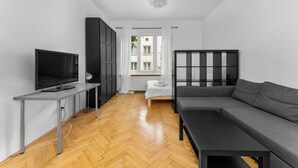 A modern living room with a TV, sofa, and a dining table. - Spokojna Comfort Studio (Kraków)