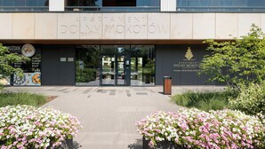 En modern byggnad med en skylt som visar texten ”APARTMENTY DOLNY MOKOTOW” och en logotyp för ”GROZONE”.