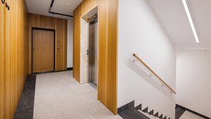 En modern hall med träpanel, en trappa och en hiss.