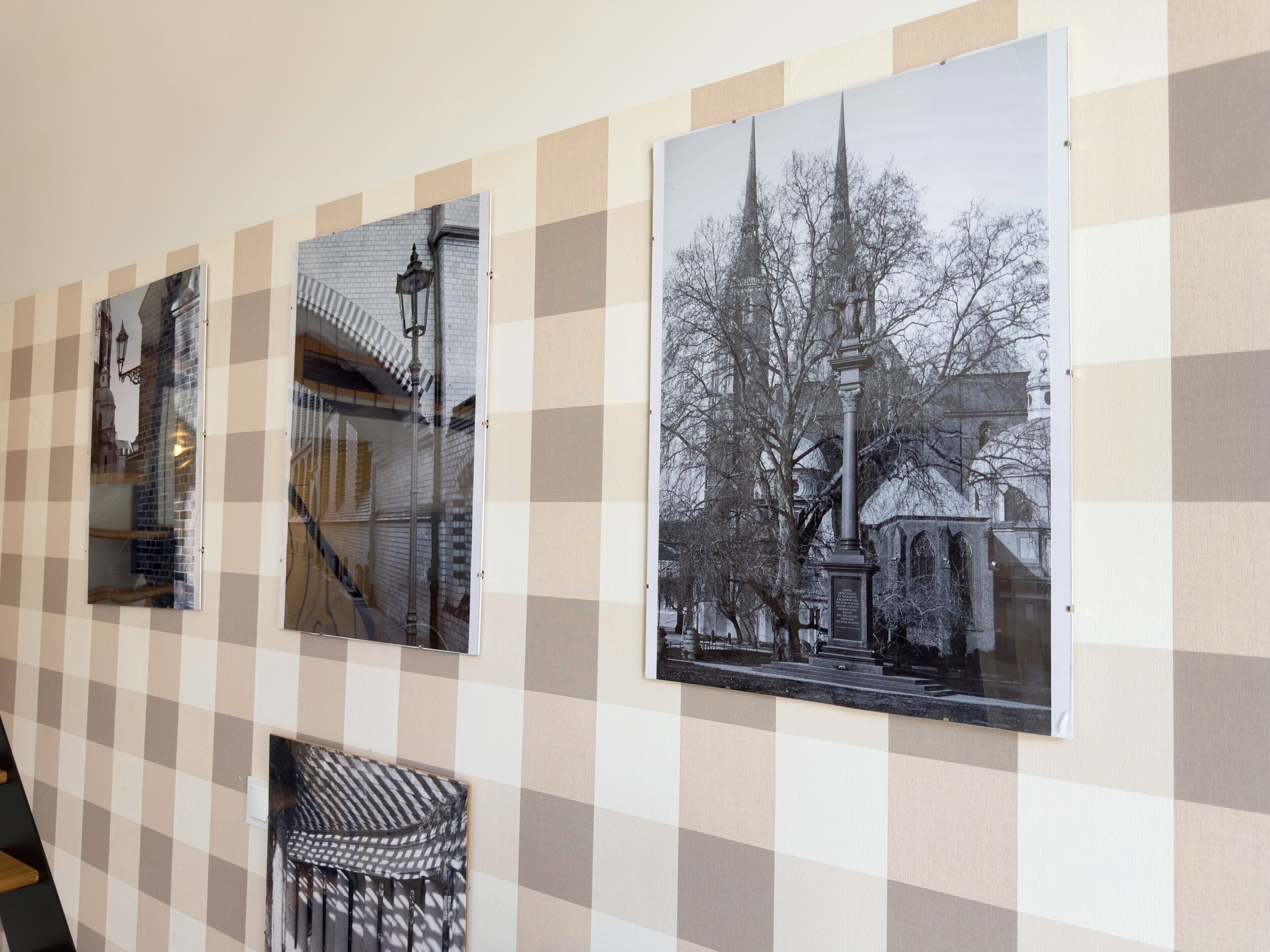 A wall with three framed photographs depicting architectural structures.