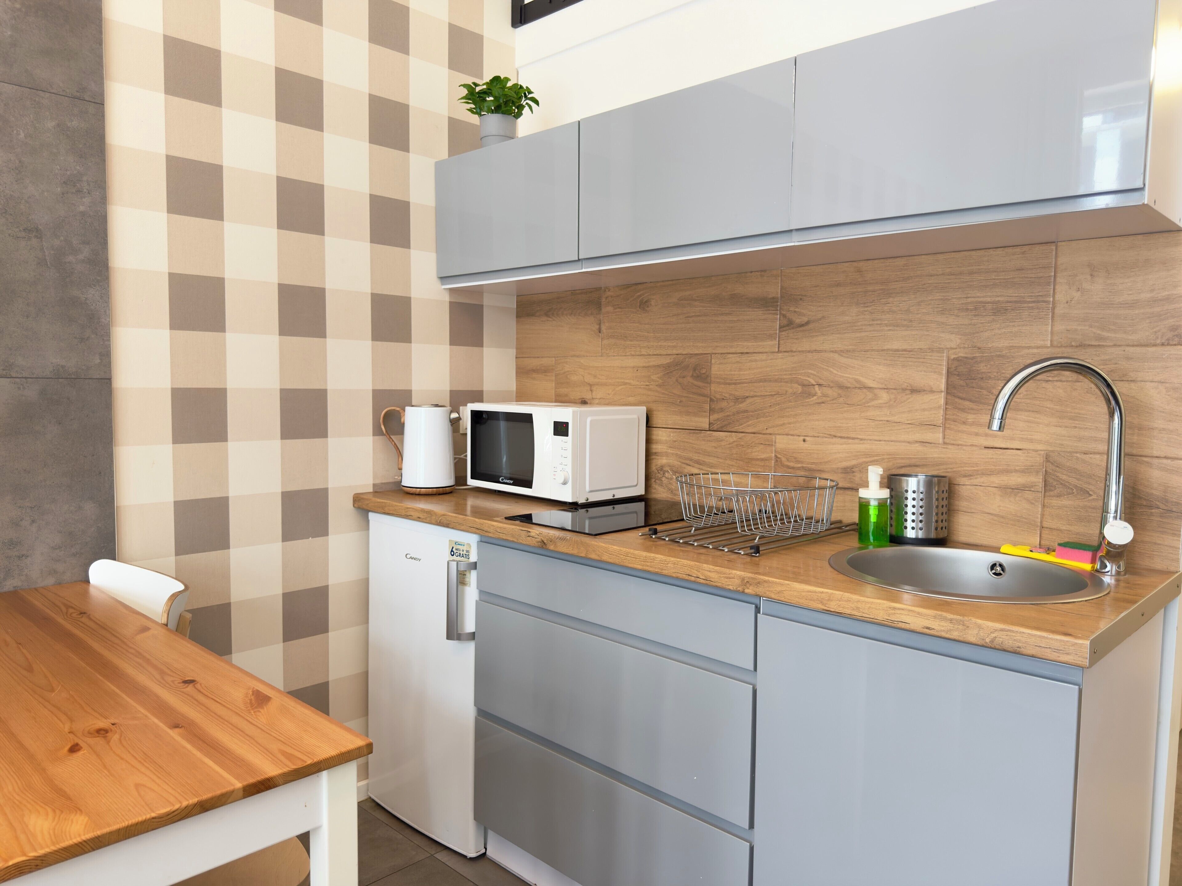 Une cuisine compacte équipée d’un four à micro-ondes, d’une bouilloire, d’un évier et d’un petit réfrigérateur.
