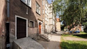 A building with a staircase leading to a door, a visible window, and a tree in the background. - Heart of Gdańsk Mariacka Apartment (Gdańsk)