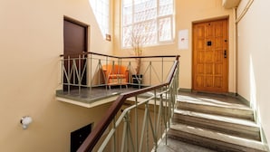 A staircase with a metal railing, a wooden door, and a window with a view of a building. - Heart of Gdańsk Mariacka Apartment (Gdańsk)
