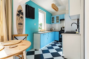 Une cuisine avec des meubles bleus, un carrelage à motifs et une décoration sur le thème du surf.