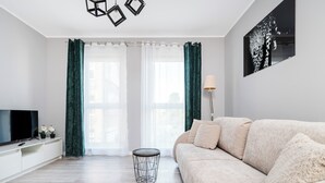 En moderne stue med sofa, TV og lampe.