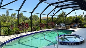 A swimming pool with a glass enclosure, surrounded by lounge chairs and potted plants. - Golf Retreat - Pool, Spa & Fire Pit (Rotonda West)