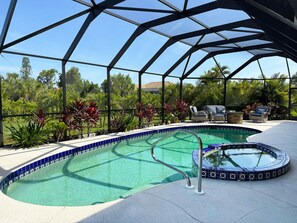 A swimming pool with a glass enclosure, surrounded by lounge chairs and potted plants. - Golf Retreat - Pool, Spa & Fire Pit (Rotonda West)