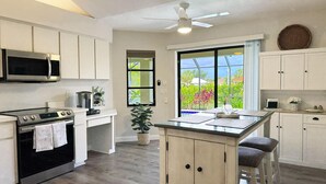 A kitchen with a central island, a microwave, an oven, and a ceiling fan. - Golf Retreat - Pool, Spa & Fire Pit (Rotonda West)