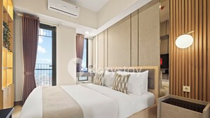 Quarto de hotel moderno com uma cama grande, mesas de cabeceira, um guarda-roupa de madeira e vista para a cidade.