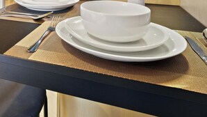 Mesa posta com pratos, tigelas, talheres e um jogo americano.