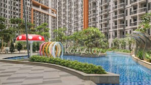 Piscina com deck revestido, rodeada por vegetação e um edifício de apartamentos moderno ao fundo.