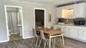 Una cocina moderna con armarios blancos, una mesa de comedor de madera y un microondas.