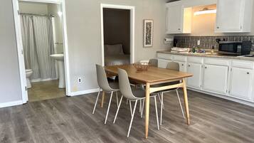 Une cuisine moderne avec des meubles blancs, une table à manger en bois et un four à micro-ondes.