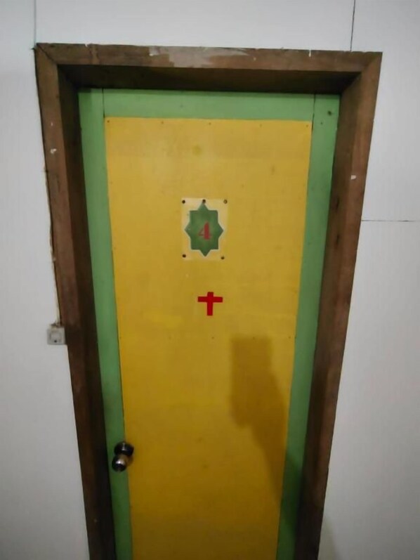 Puerta con marco verde y panel amarillo, que muestra una cruz roja y el número 4.