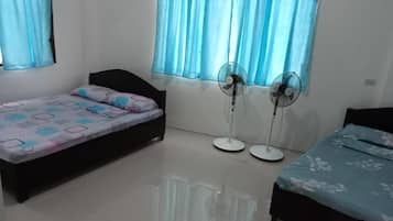 Una habitación con una cama, una mesita y dos ventiladores de pie.