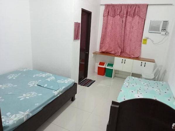 A bedroom with two beds, a wardrobe, a radiator, and a door.