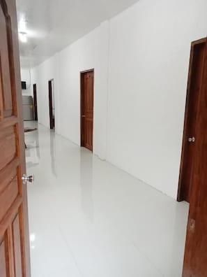 A corridor with white walls and wooden doors.