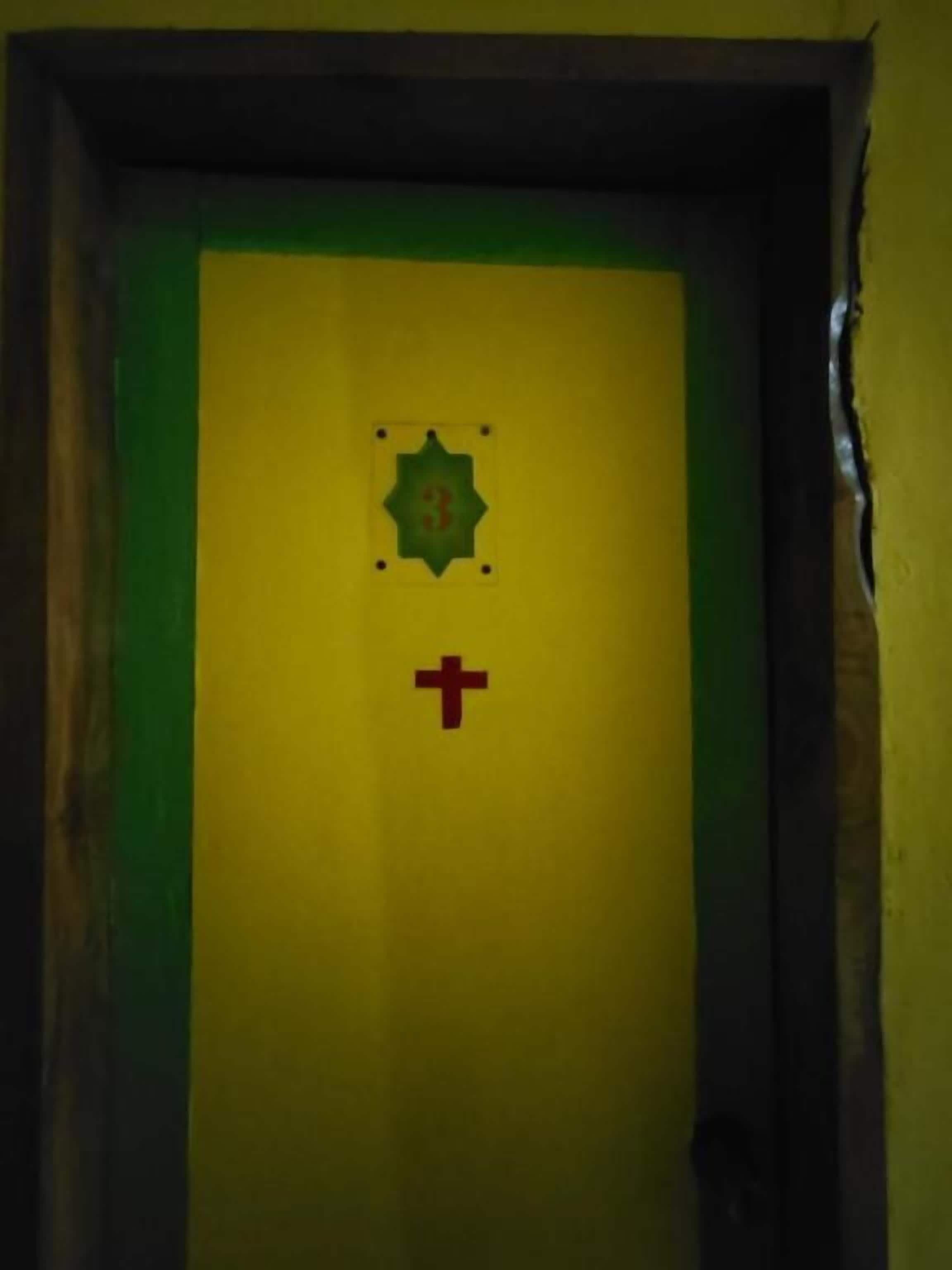 Uma porta com esquema de cores verde e amarelo, um símbolo de estrela e uma cruz vermelha.