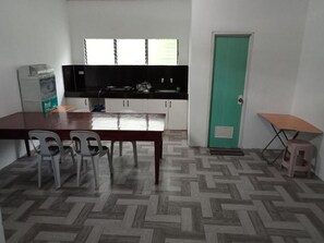 A compact kitchen with a dining table, chairs, and a small stool.