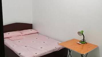 Una camera piccola con un letto singolo, una scrivania in legno e una lampada da scrivania verde.