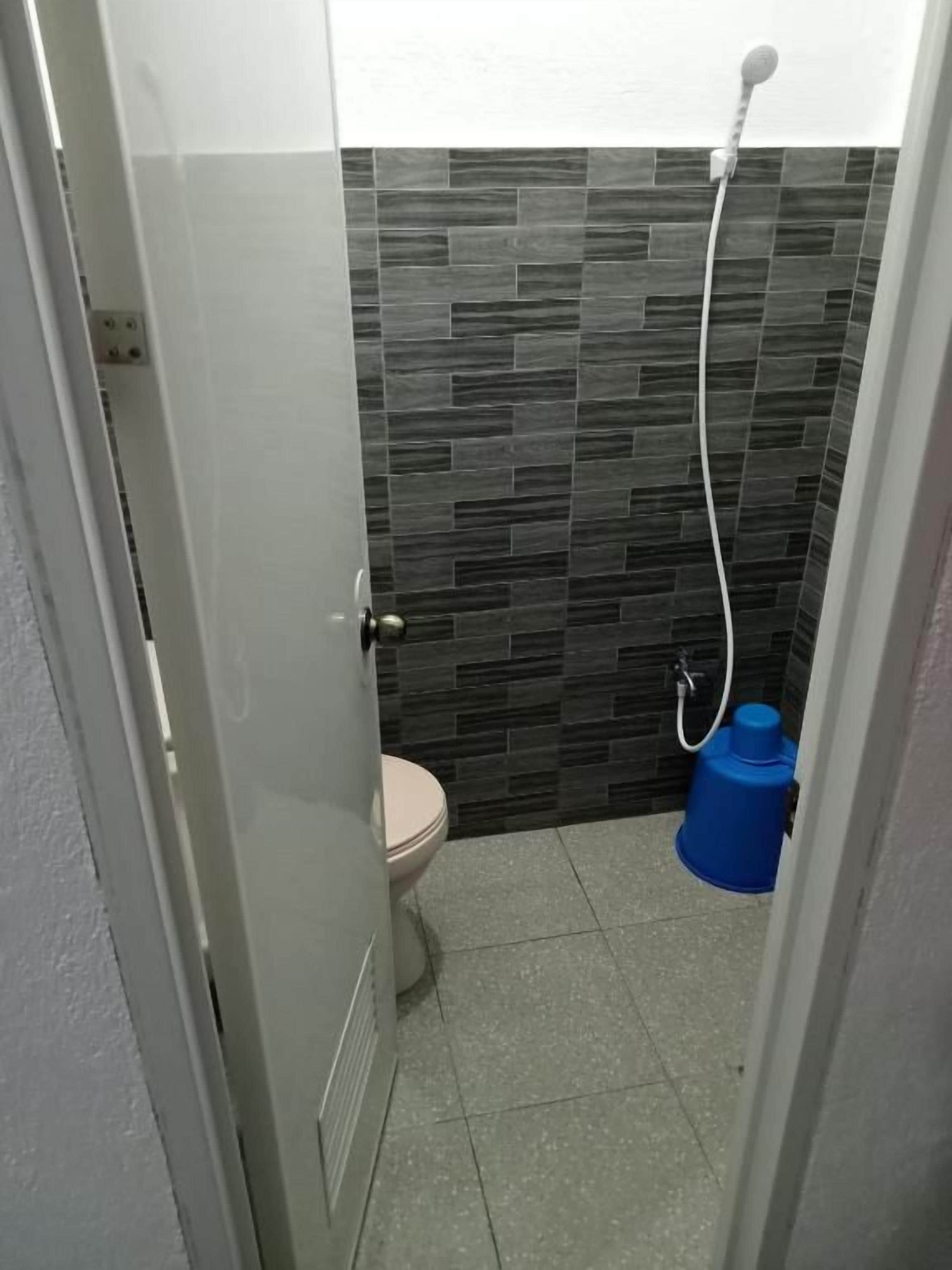 A bathroom with a toilet, a shower, and a blue water tank.