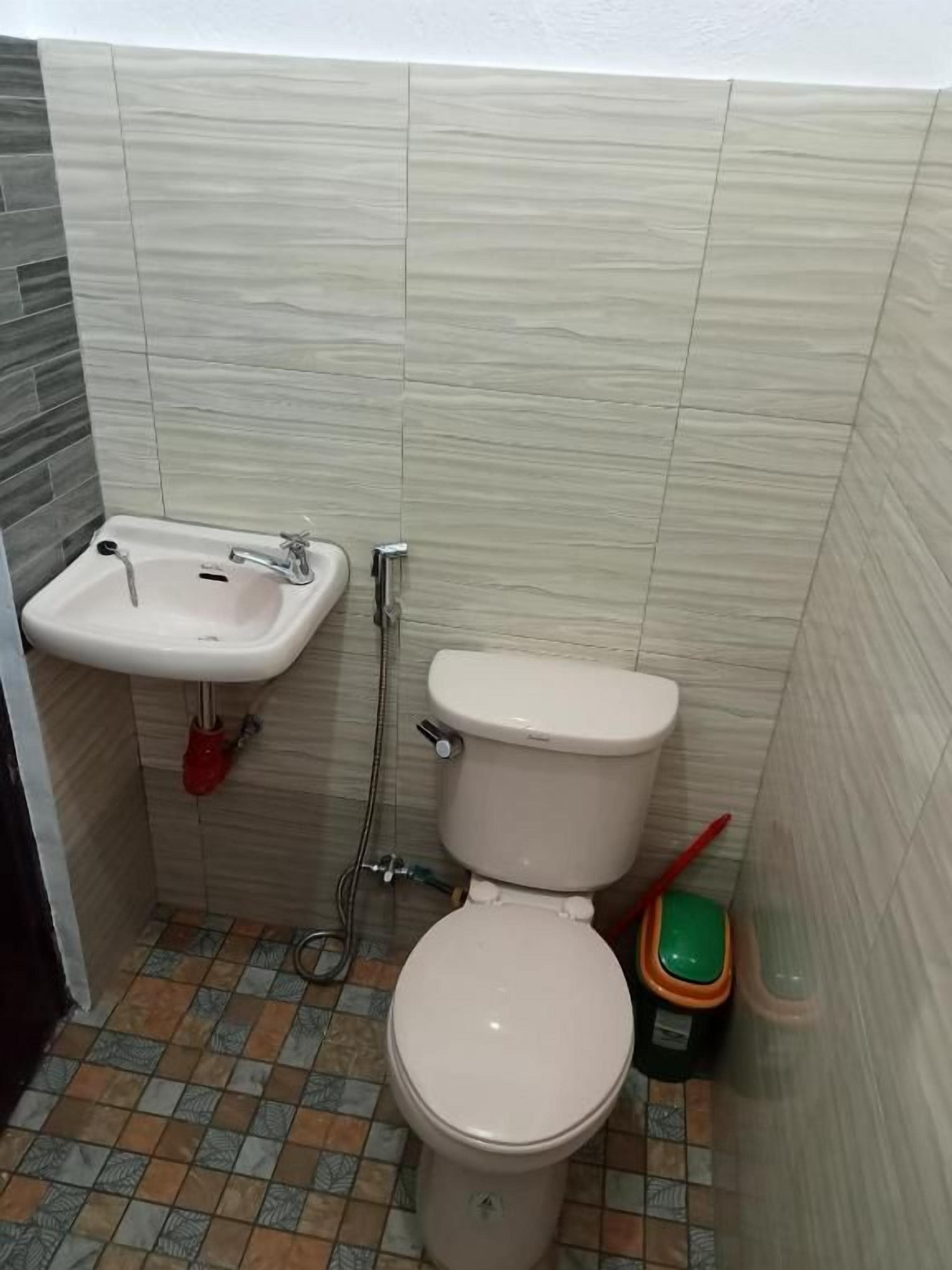 A small bathroom with a toilet, sink, and shower.