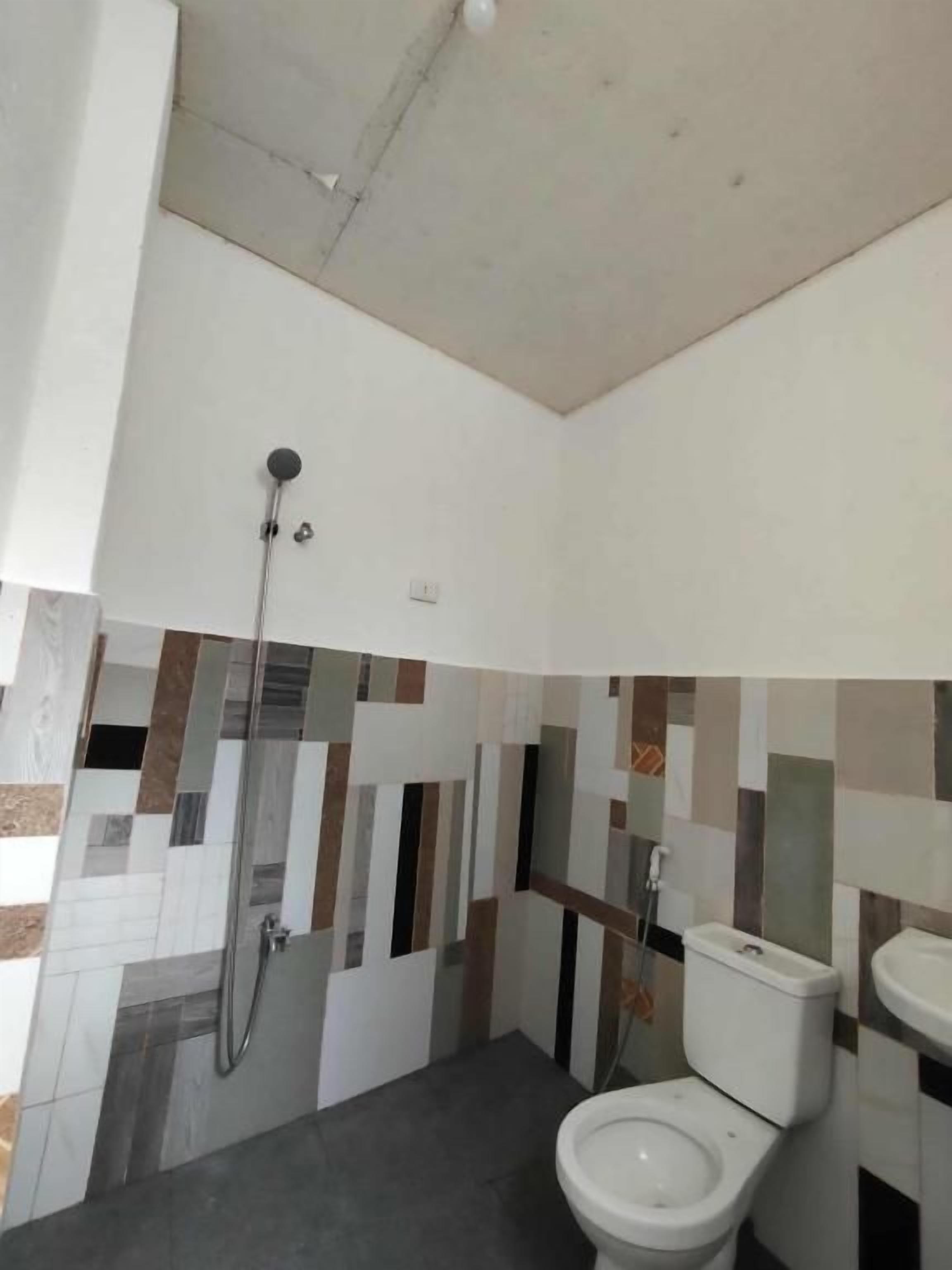 Ein Badezimmer mit Toilette, Dusche und Fliesen.