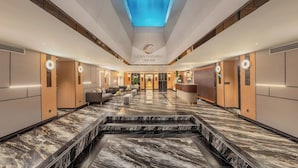 A hotel lobby with a marble floor, a reception desk, sofas, and a ceiling with a water feature.