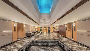 A hotel lobby with a marble floor, a reception desk, sofas, and a ceiling with a water feature.
