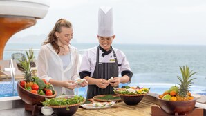 A chef preparing food on a boat with a view of the ocean.