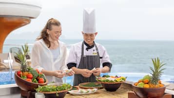 A chef preparing food on a boat with a view of the ocean.