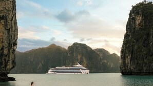 A cruise ship on a calm body of water with rocky cliffs on either side.