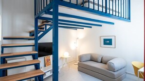 Ein modernes Interieur mit einer blauen Treppe, einem grauen Sofa und einem kleinen Tisch.