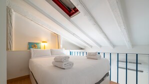Ein Schlafzimmer mit Bett, Kissen, Lampe und einem Gemälde.