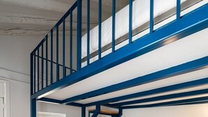 Ein mehrstöckiger Raum mit einer blauen Treppe, einem Flachbildfernseher, einer Lampe und einem Sofa.